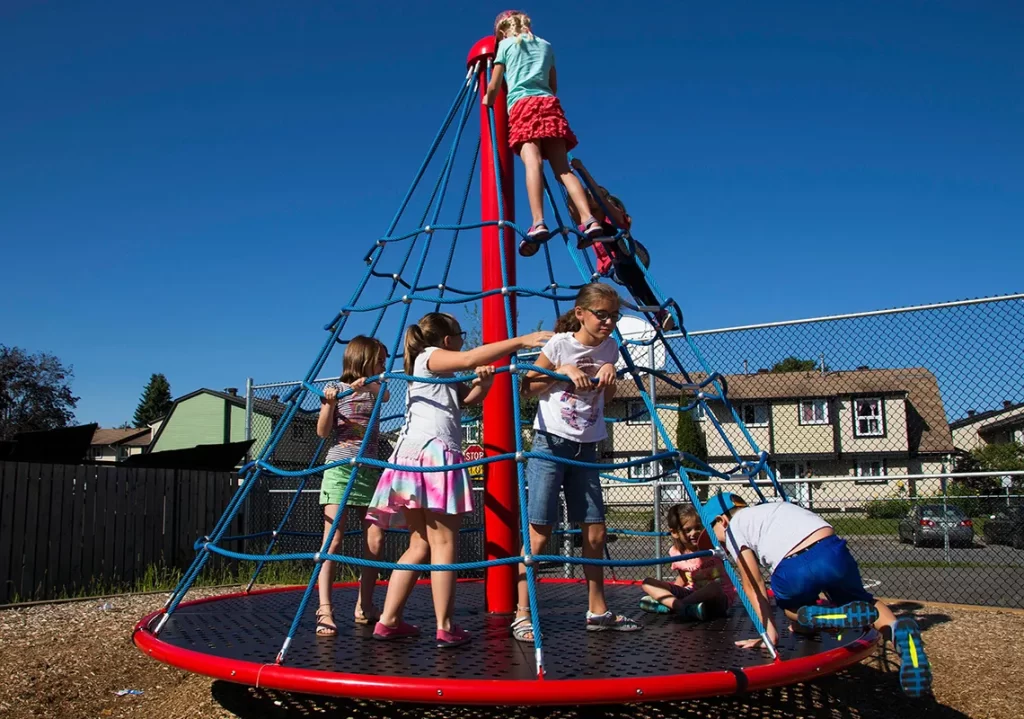 Kids playing on rotating climber at neighborhood playground