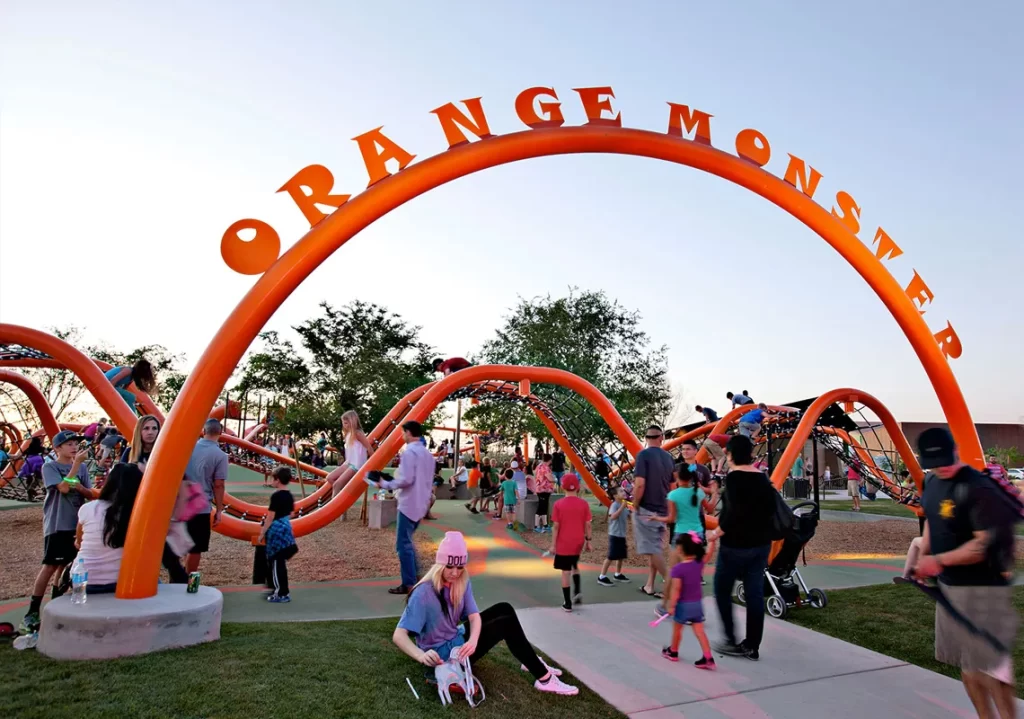 Large Orange ropes course playground with families and children playing