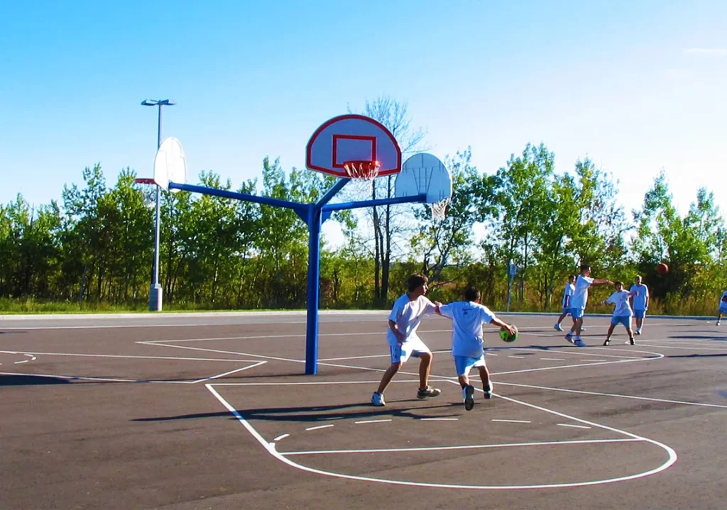 Kids playing basketball on outdoor court with multiple hoops