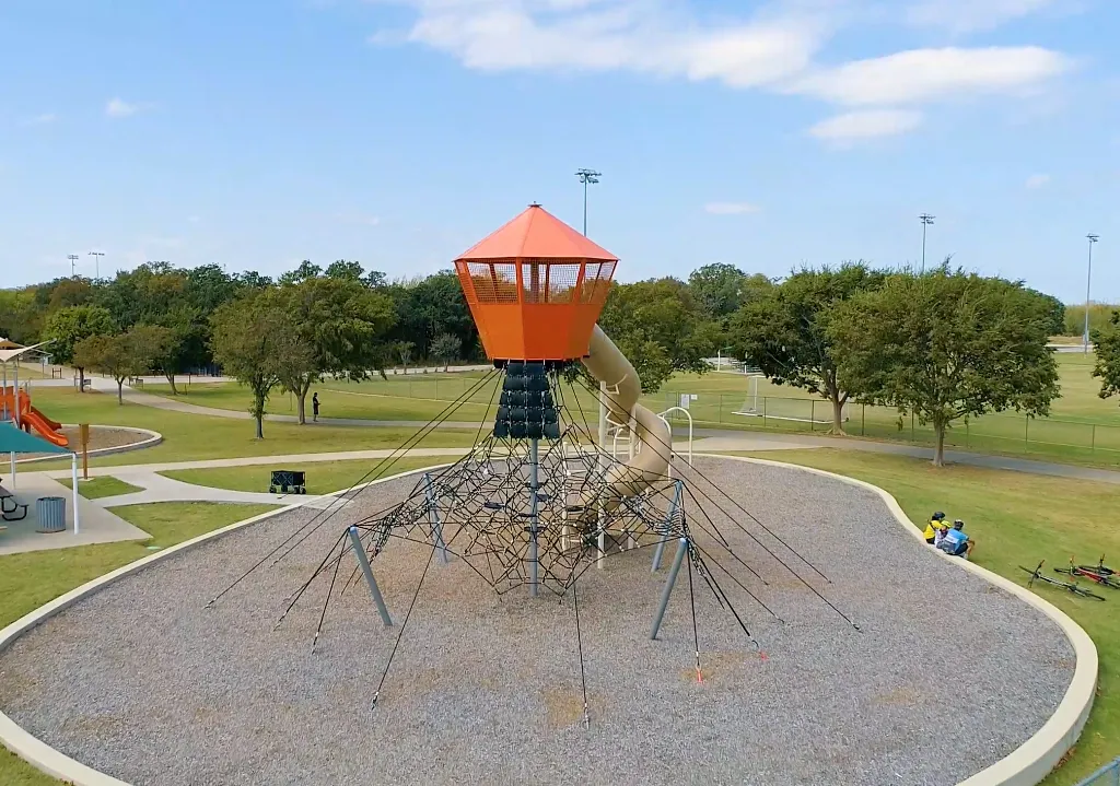 Tall rope climbing tower with spiral slide at modern playground