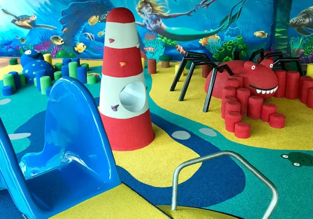 Colorful ocean-themed playground with a blue slide, red crab structure, and sea life mural