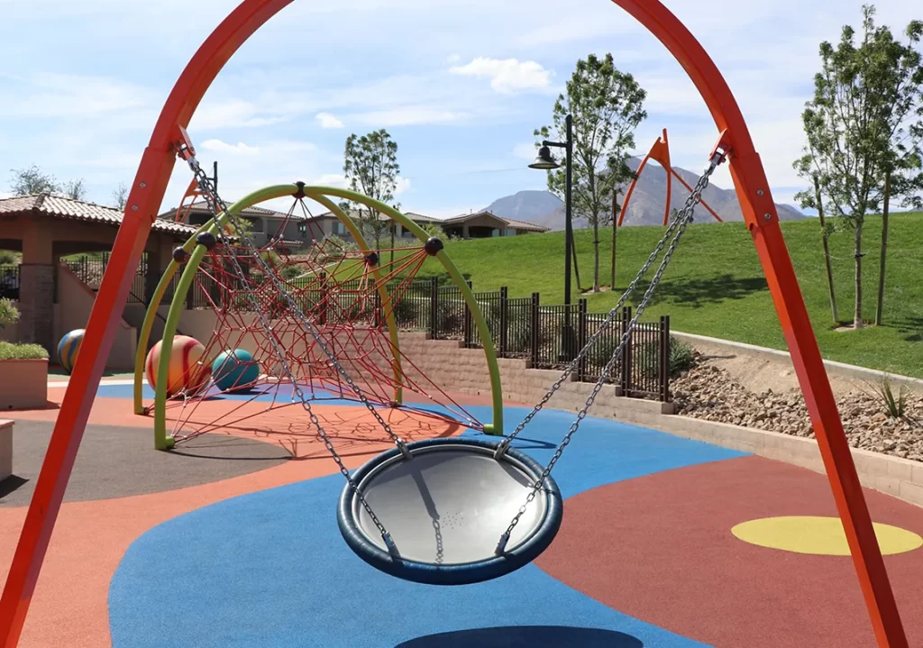 Modern playground featuring a red Biggo swing, and soft blue and orange surface